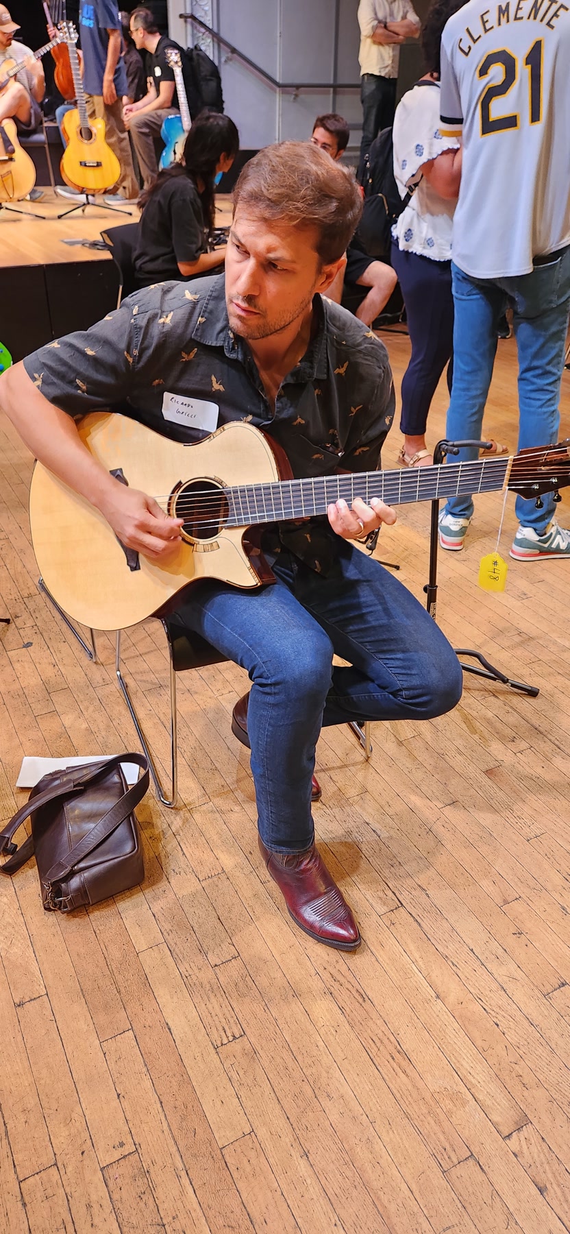 A guitarist trying a modern cutaway acoustic guitar at Brooklyn Guitar Feast III.