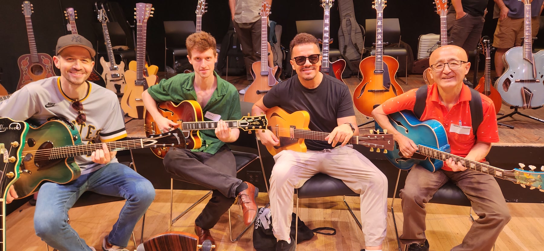 Four guitarists seated together with instruments at Brooklyn Guitar Feast III.